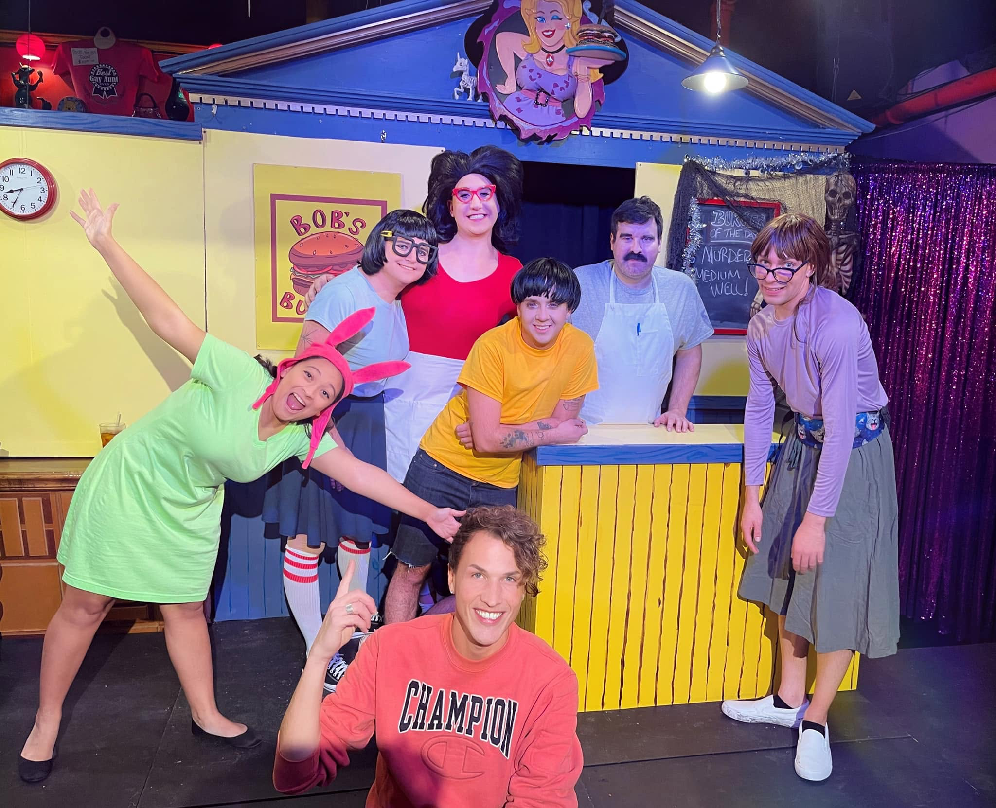 Seven company members pose on a Bob’s Burgers set.