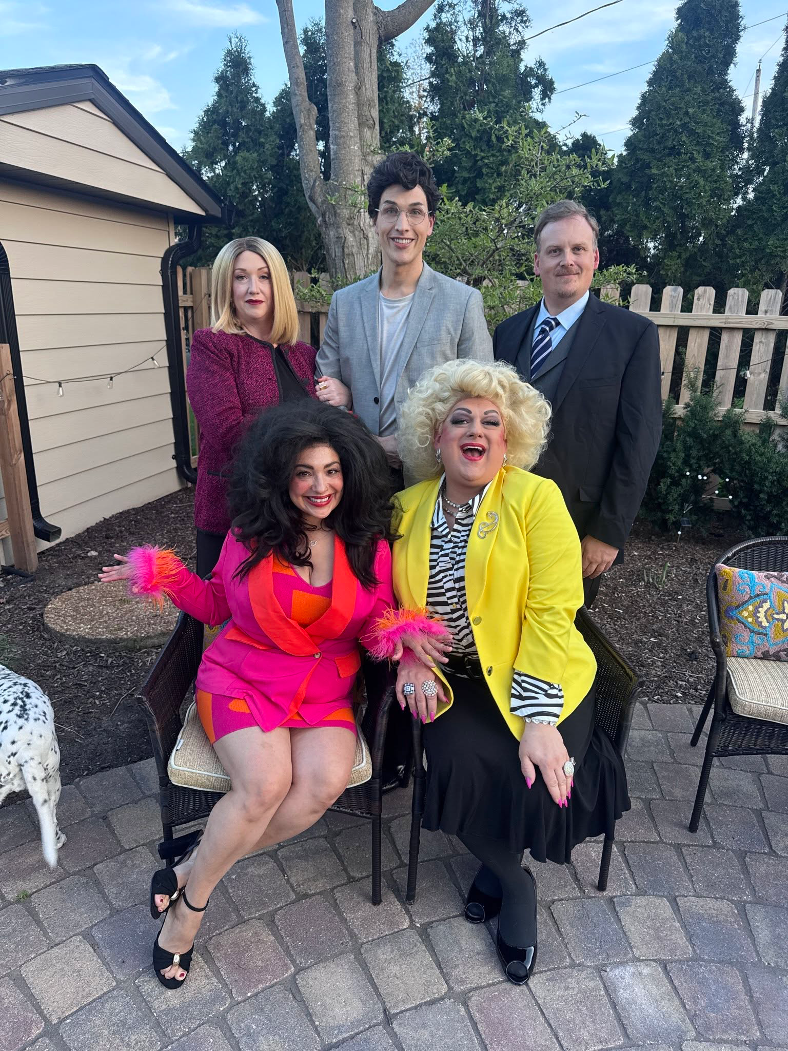 Five company members in costume pose for a group portrait on an outdoor patio.